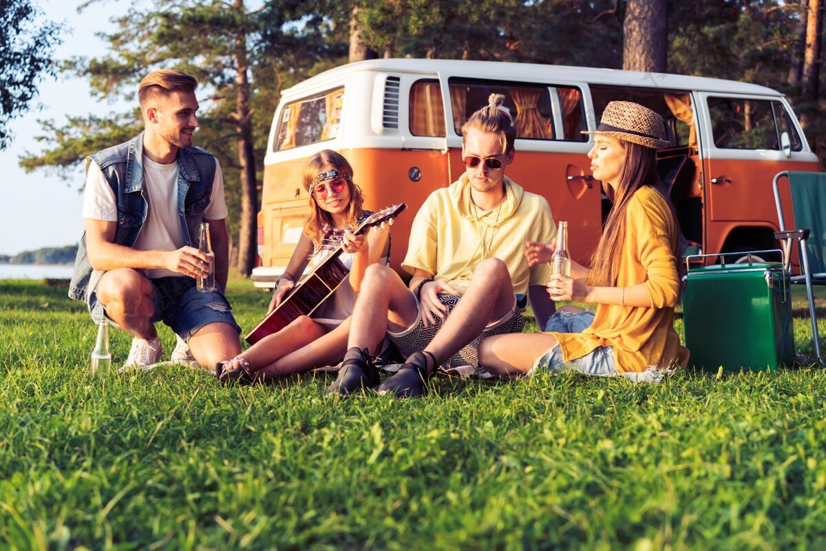女性在夏天的节日里 时髦的朋友们坐着露营车户外热复兴