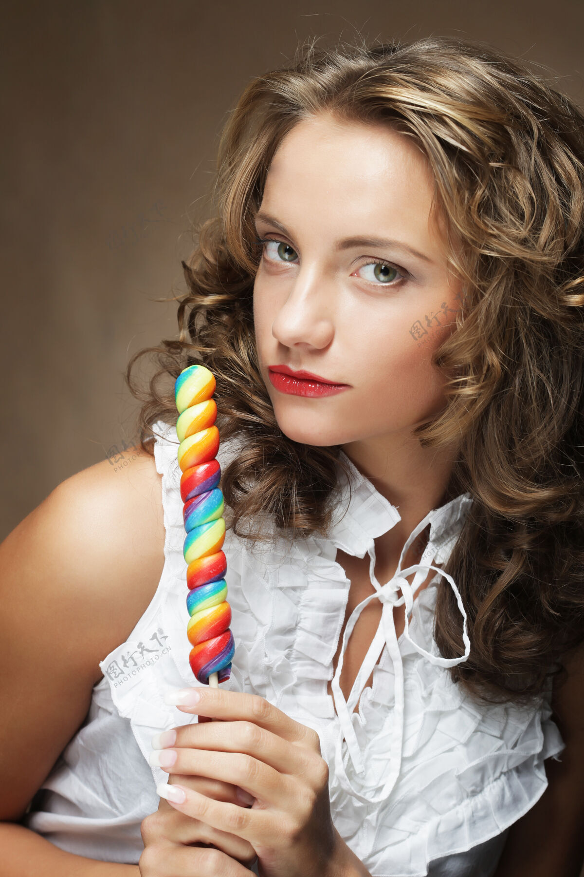 卷曲年轻漂亮的女人用五颜六色的棒棒糖白天黑发女人