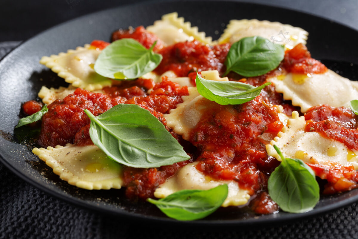 馅料美味的意大利馄饨配番茄酱和罗勒 放在深色盘子里食物菜肴香草