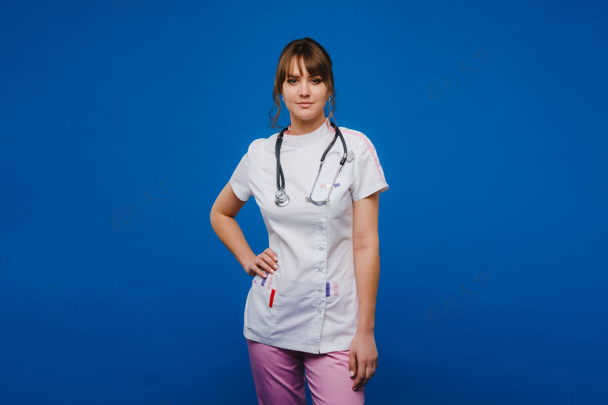 朋友年轻的女医生用听诊器隔离在蓝色背景上年轻实习生专业