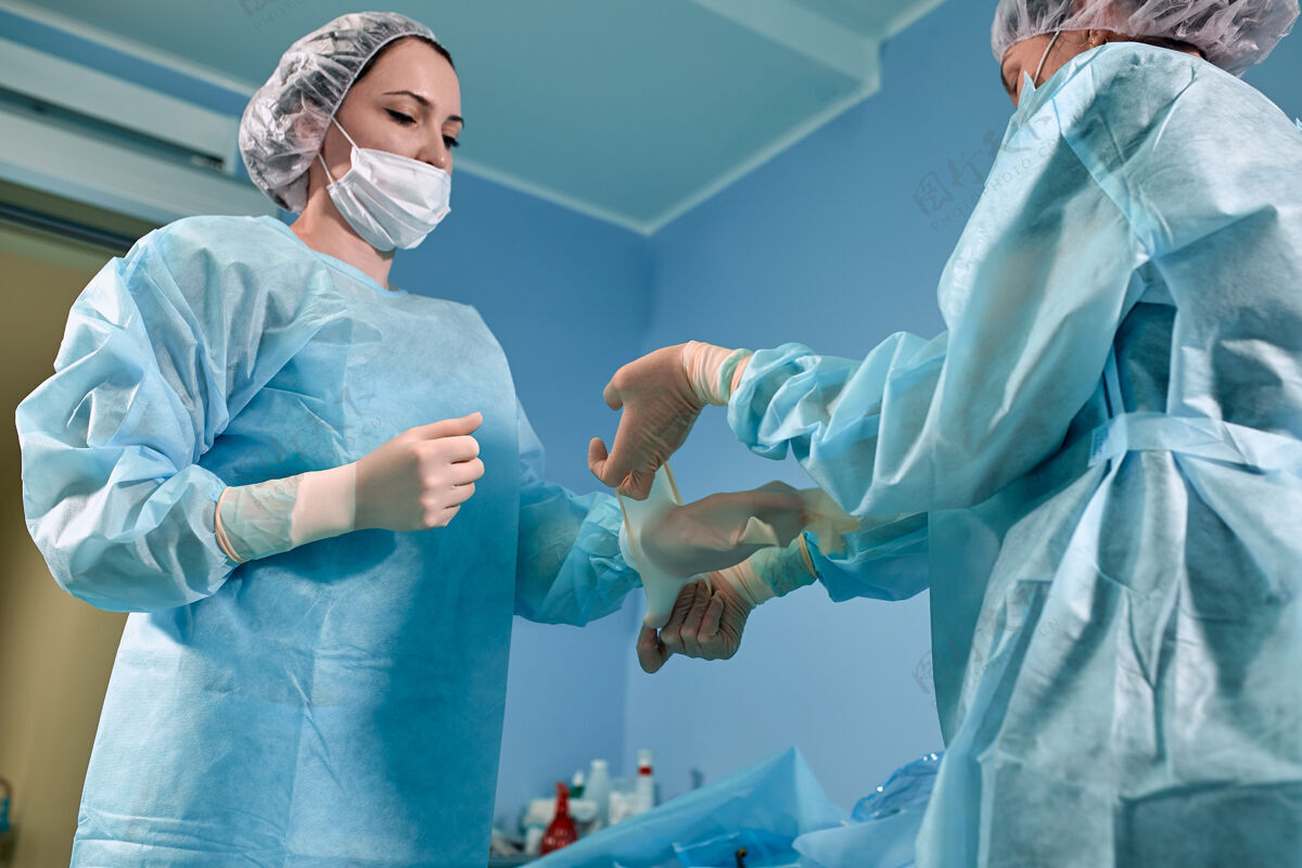助理一队外科医生正在为外科手术做准备外科医生在护士的帮助下穿着无菌的手术服手套口罩在重症监护室手套责任制服