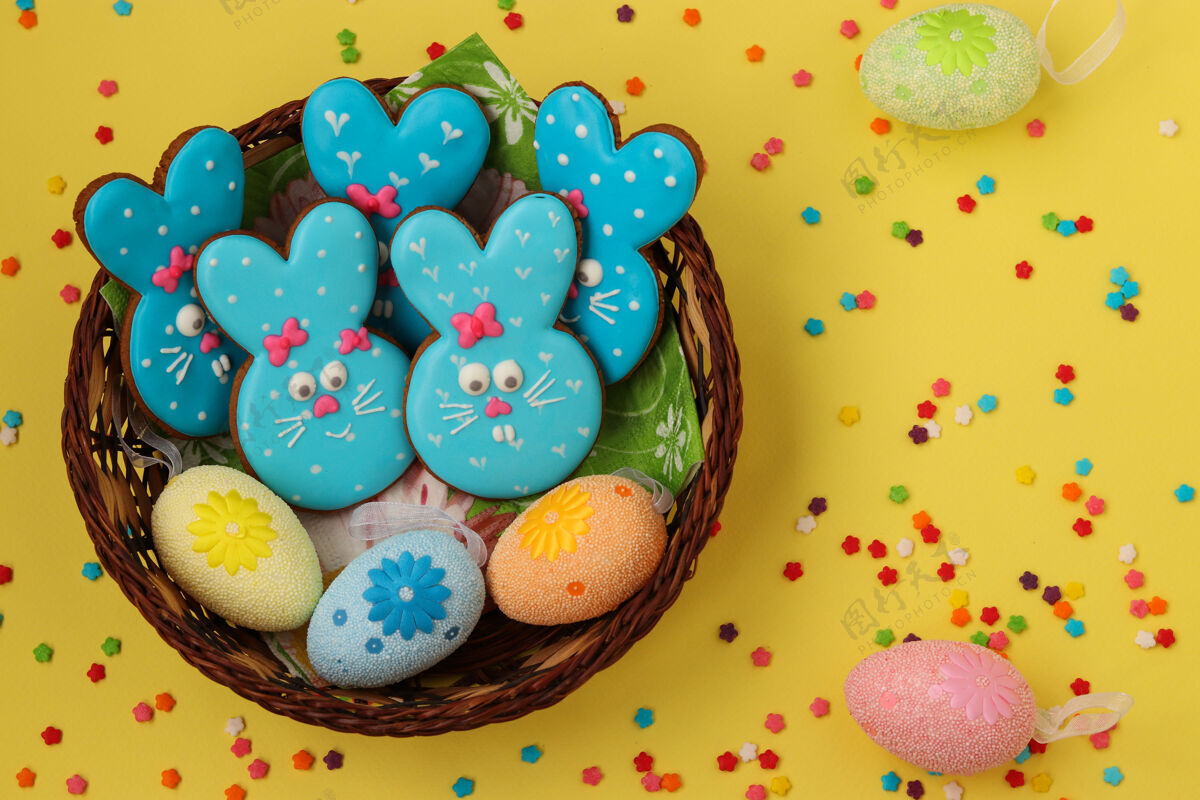 霜冻复活节搞笑的蓝兔子 自制的涂了釉的姜饼饼干放在黄色表面的柳条篮子里 顶视图招待自制糖果