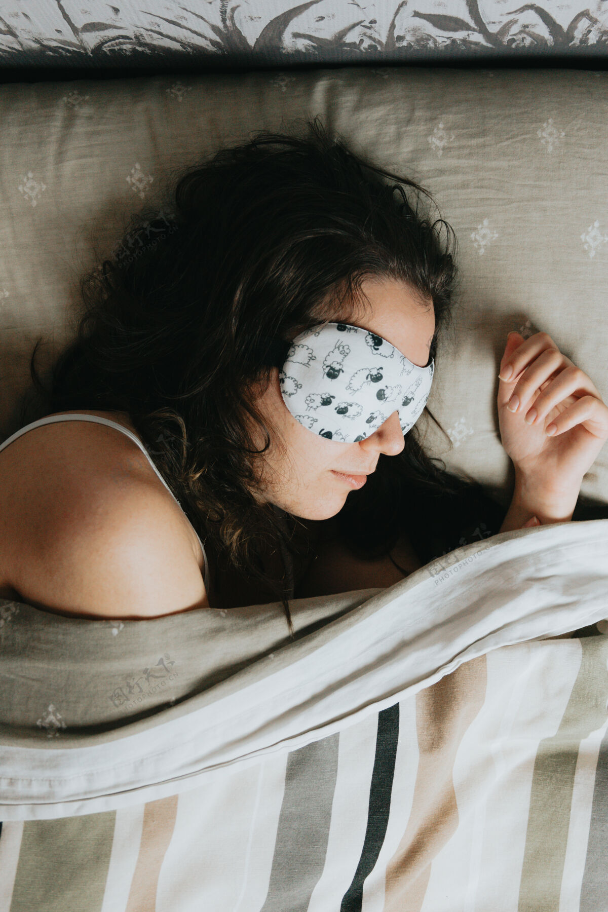 床单空中拍摄的一名年轻女子戴着白色睡眠面罩睡在床上睡觉时间青春亚麻布