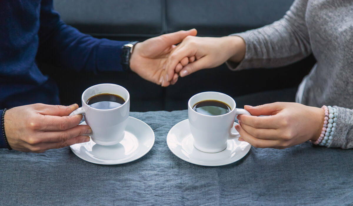 会议一男一女端着一杯咖啡坐在桌边杯子交流朋友
