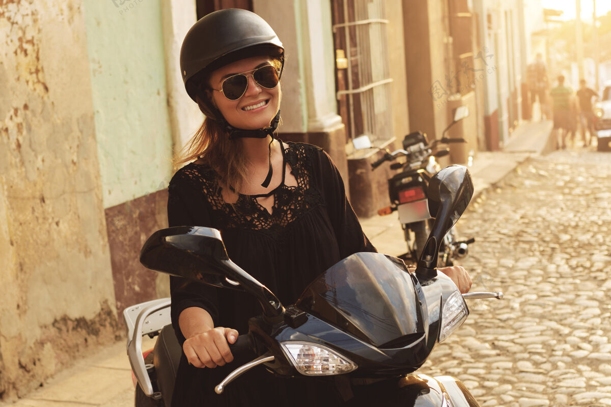 日落在老城区街道上开着摩托车的女旅行者可爱女人摩托车