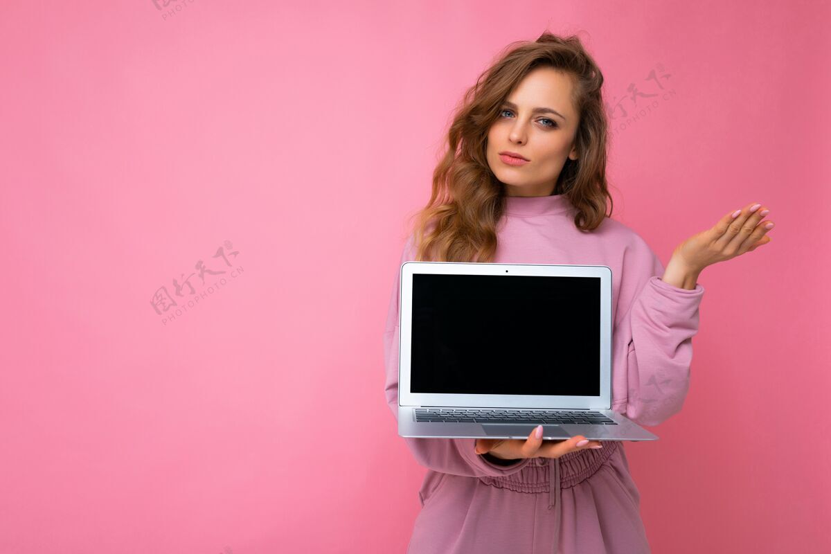 青少年一个年轻漂亮的金发卷发女人拿着一台空笔记本电脑的特写镜头青少年电子笔记本电脑