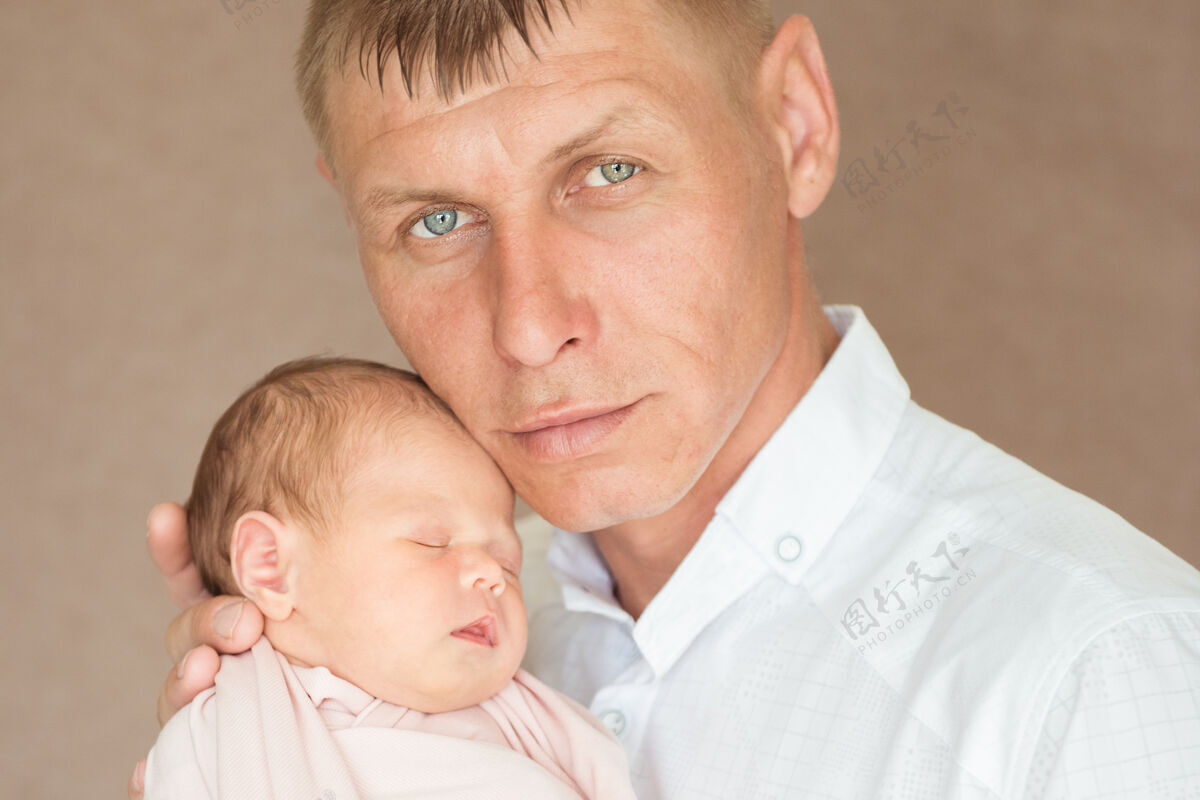 后代帅气严肃的爸爸抱着刚出生的宝宝女儿父亲的概念快乐亲子关系成人