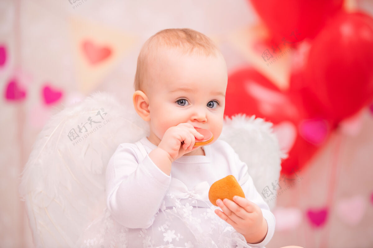 快乐一个快乐的小女孩 长着白色羽毛翅膀 吃着心形饼干女孩花环庆祝