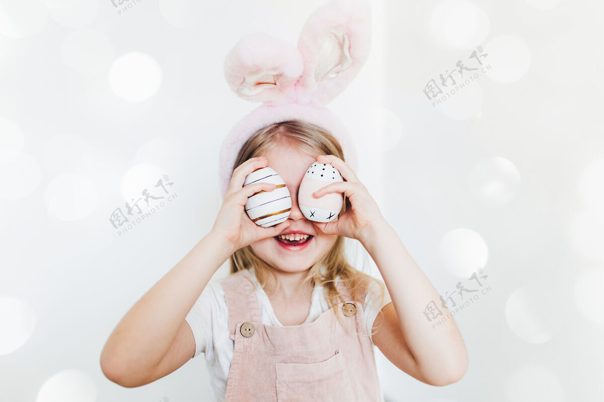 兔子带着复活节彩蛋和兔子耳朵帽子的小女孩童年女传统