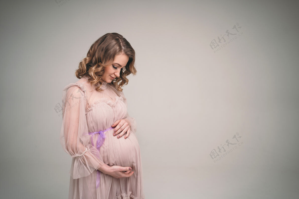 爱一个怀孕的女孩抱着她的肚子一个年轻的母亲正期待着一个孩子的出生孩子女人轻轻地抱着她的宝宝在肚子里产妇期望深情