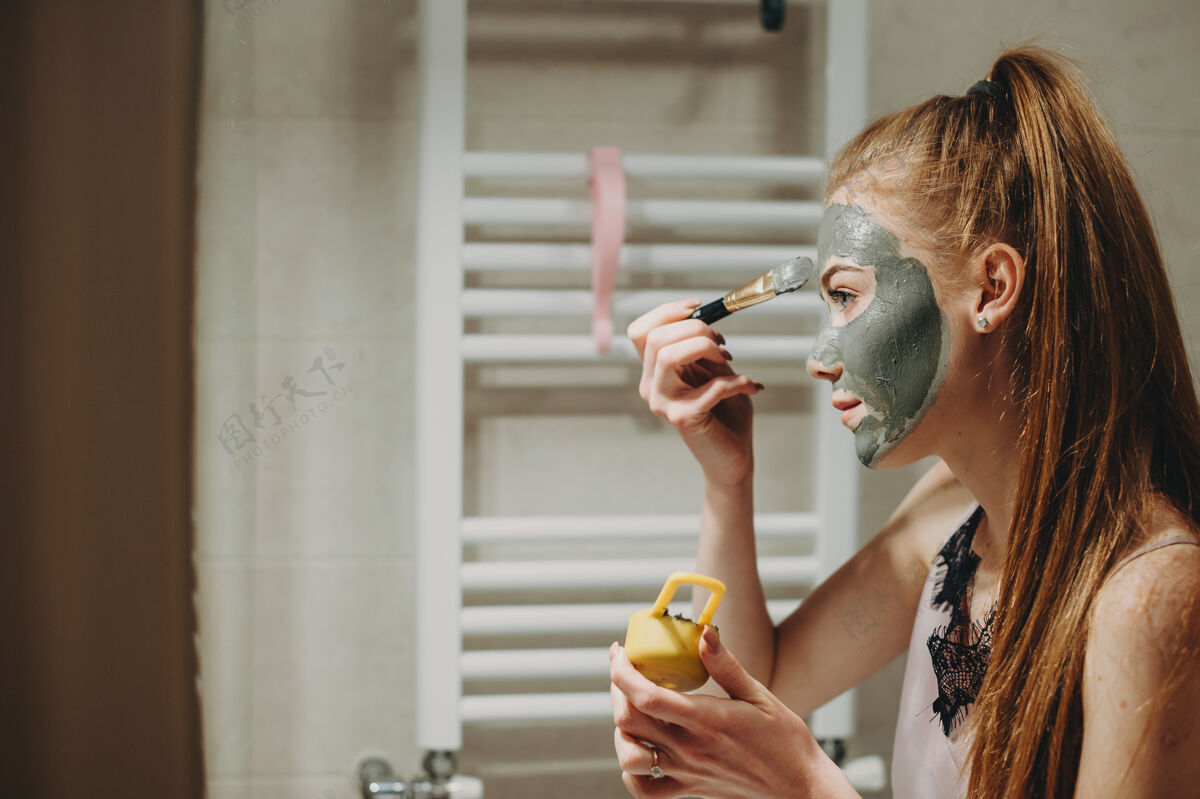 女人可爱的女人 红色的头发和雀斑在浴室里做面膜女士 水疗 刷子 有机 化妆品 头部 清洁 浴室 放松 年轻 洗澡 肖像 面部 皮肤护理 治疗 成人 卫生 漂亮 痤疮 治疗 粘土 应用 美容 清洁 自由空间 瑕疵
