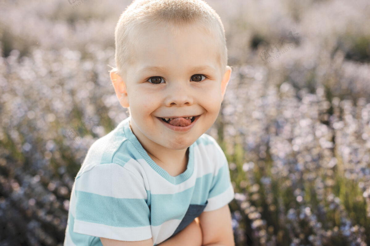 自由空间一个可爱的小男孩微笑的特写肖像在一片花丛中展示舌头气味童年孩子