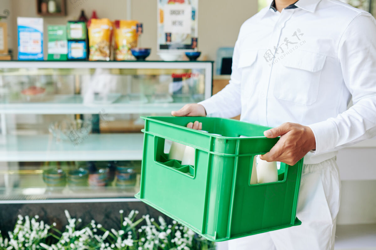 乳制品一个穿着白色制服的送货员拿着塑料牛奶箱去杂货店的剪影服务升华盒子