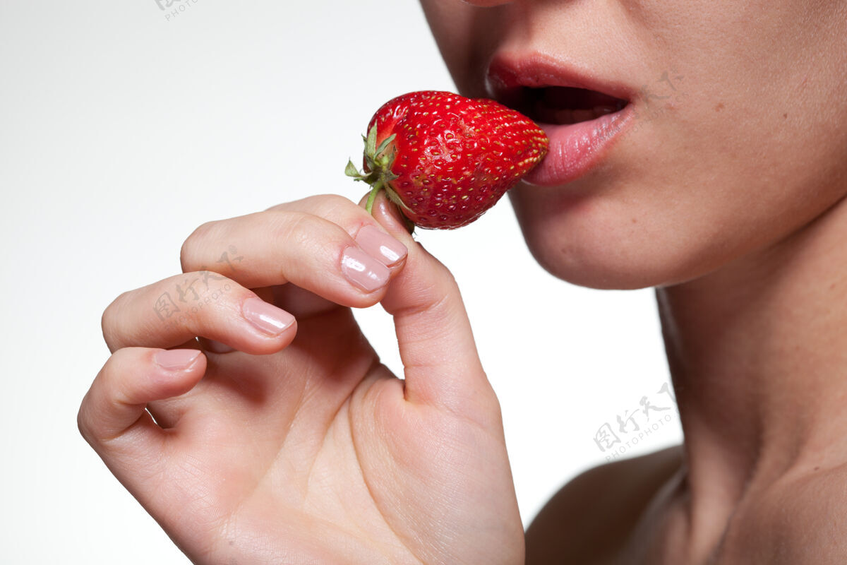 热一个年轻的女人咬着白色的草莓女性女孩新鲜