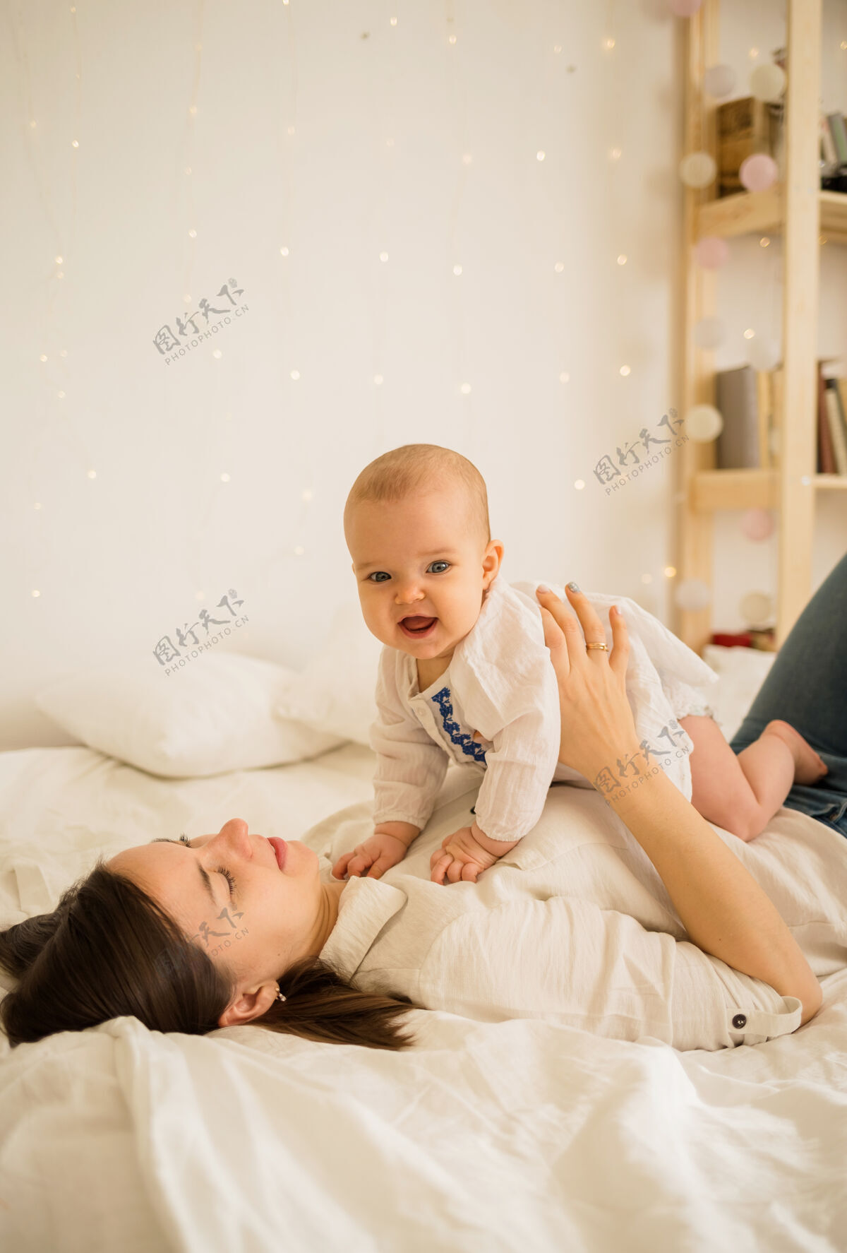 床一位母亲和她的小女儿躺在房间床上的白色毯子上的画像小年轻新生儿