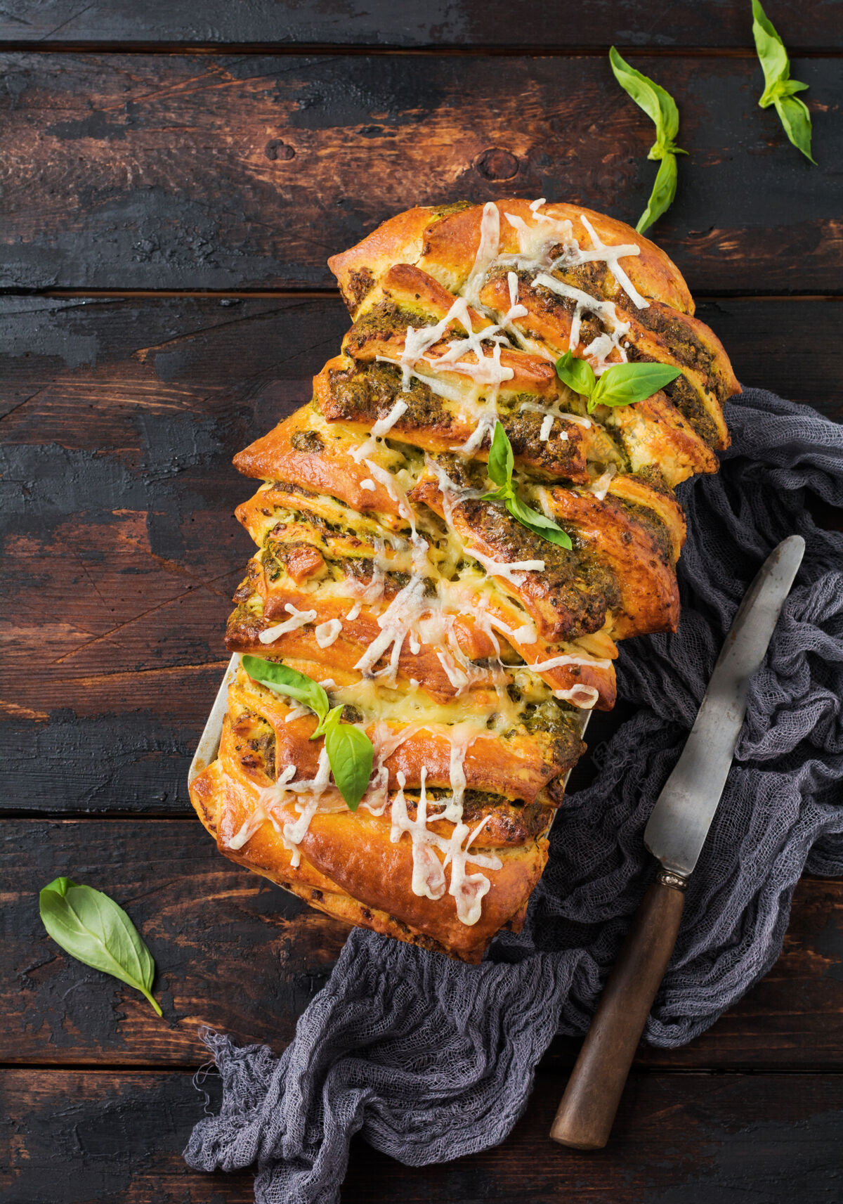 切割自制的编织香蒜面包 用罗勒叶装饰在简单的木头上表.意大利语传统的面包收到空格.top查看沙司烹饪谷类