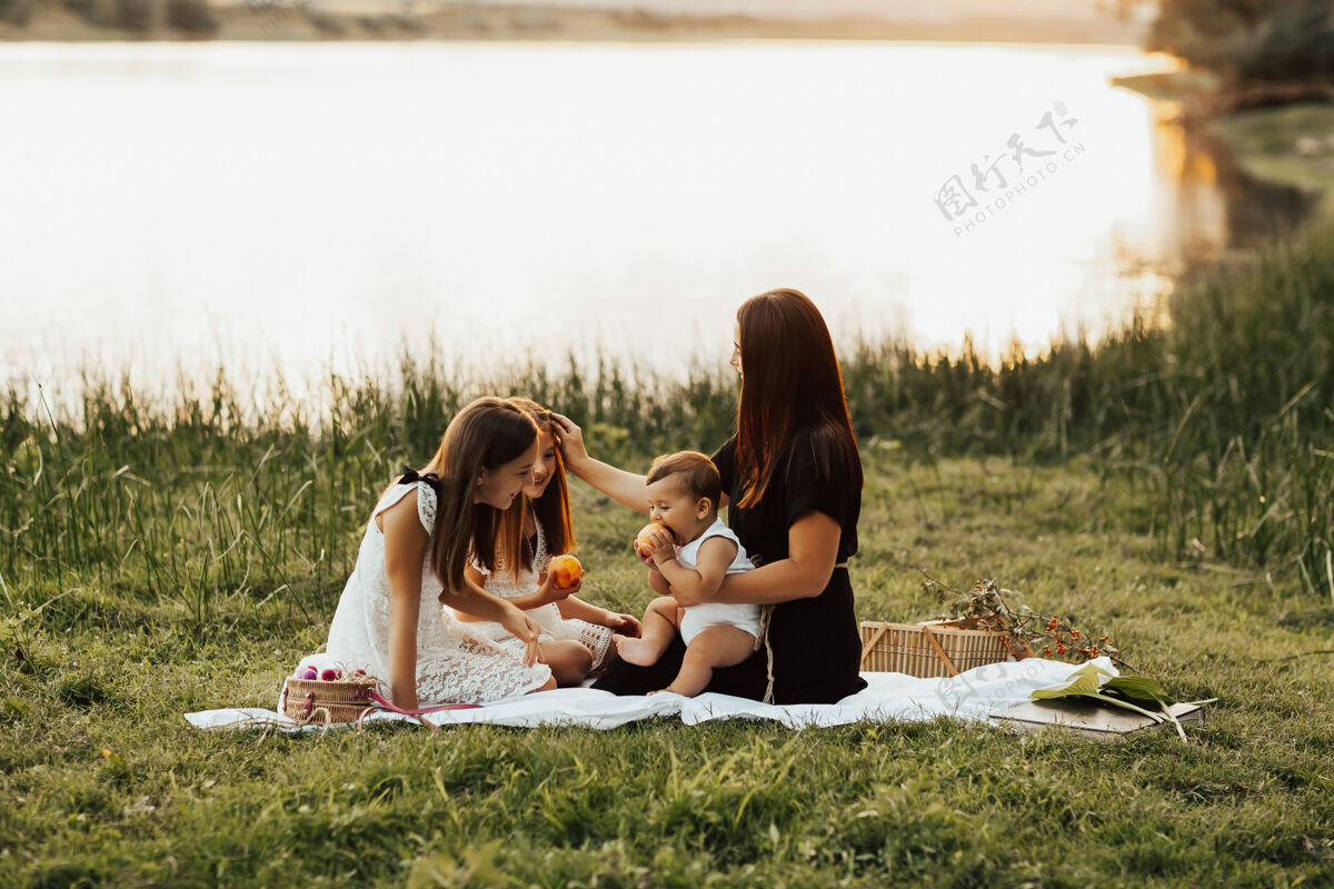 吸引快乐的一家人在河边享受大自然的野餐夏天野餐衣服