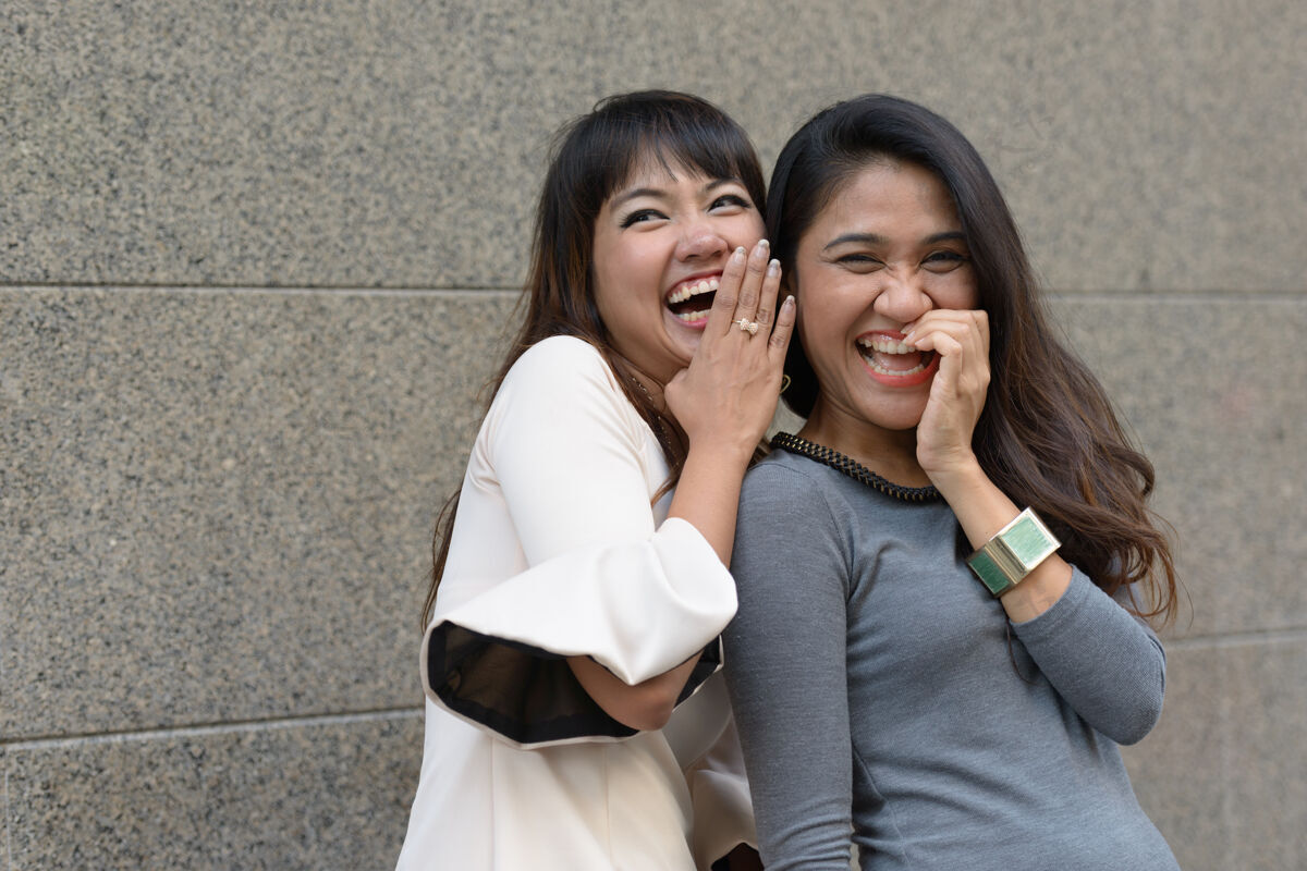 亚洲两位年轻的亚洲女商人在城市户外的合影耳语夫妇市中心