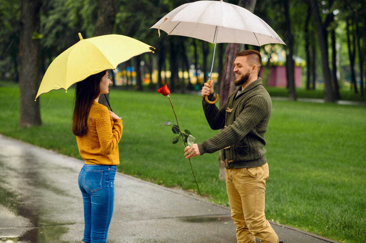 家庭雨中公园浪漫约会戴曼带着红玫瑰在小路上等着他的女人 小巷里天气潮湿妻子森林夫妇