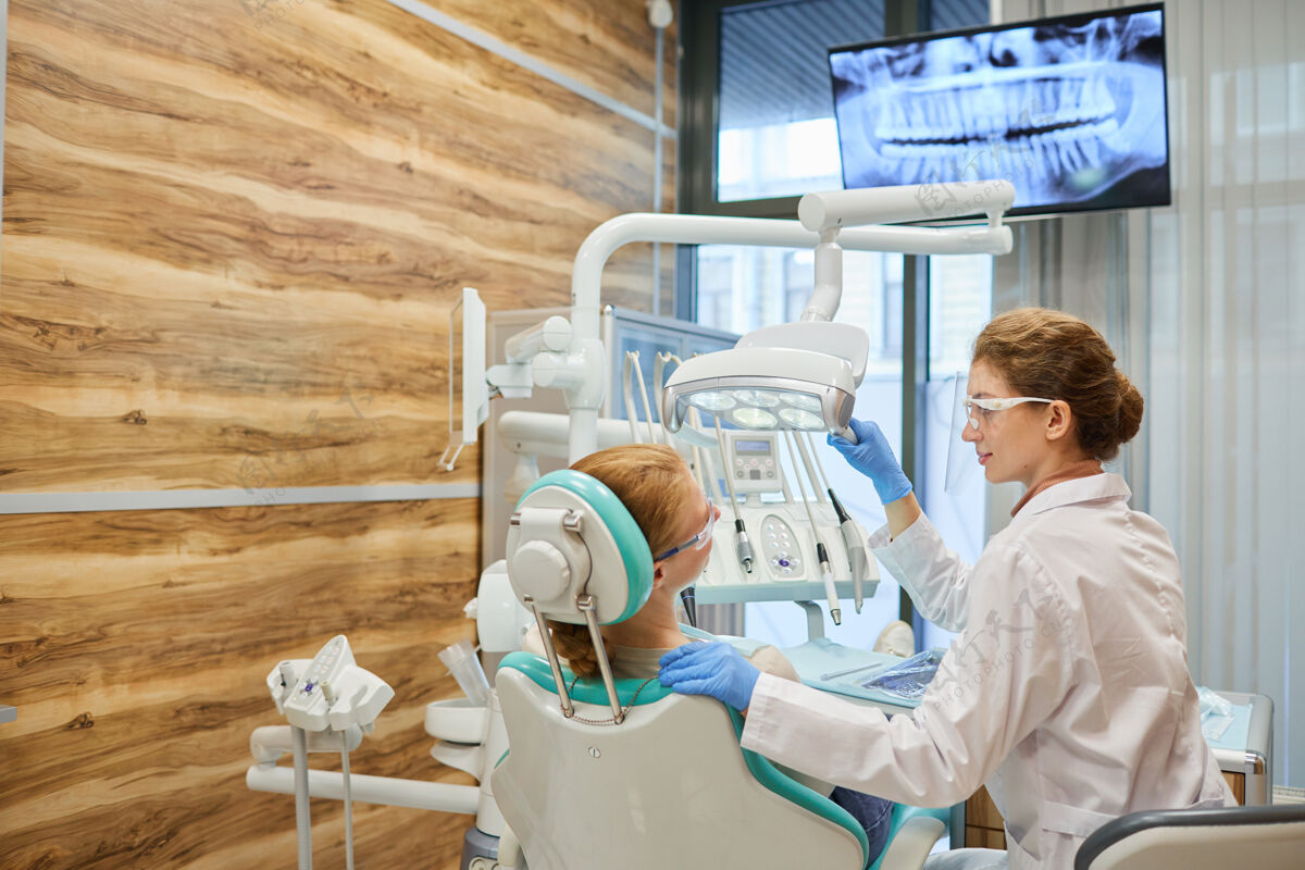 医疗职业牙医给她治牙时 病人正看着显示器 面前有x光片患者外科医生牙医办公室