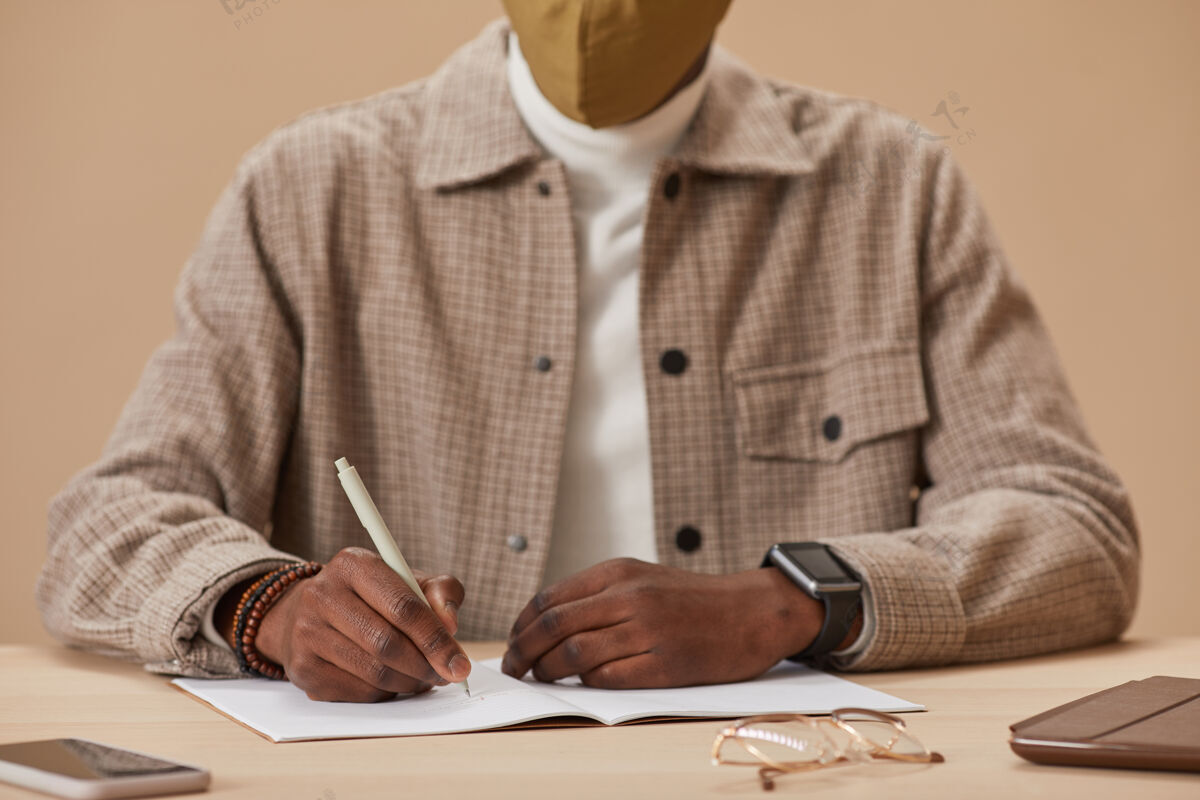 写作一个男人坐在桌子旁在笔记本上做笔记的特写镜头职业计划工作