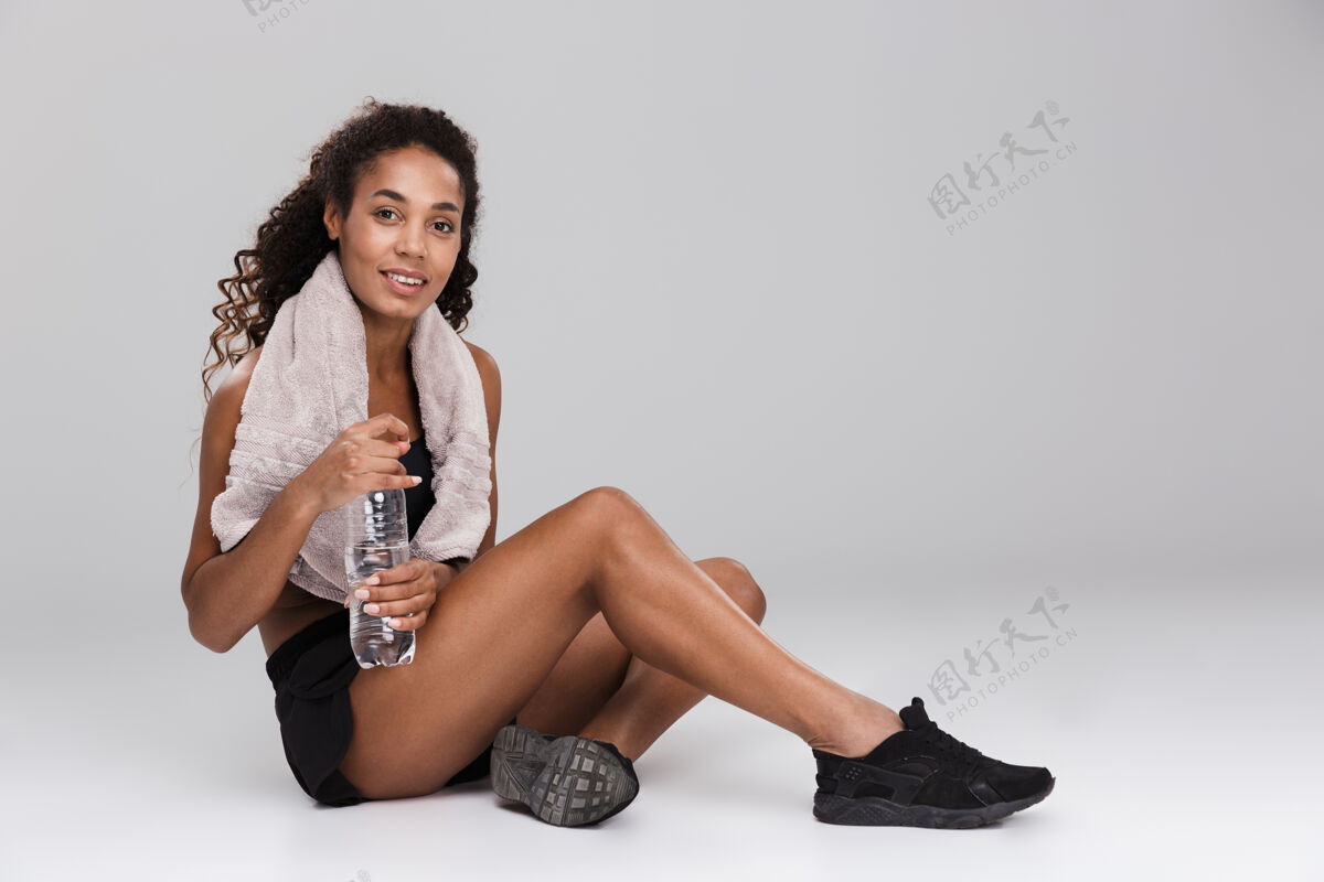 加勒比一位微笑的年轻非洲女运动员的肖像 在灰色的墙壁上独自训练后休息 喝水微笑非洲看