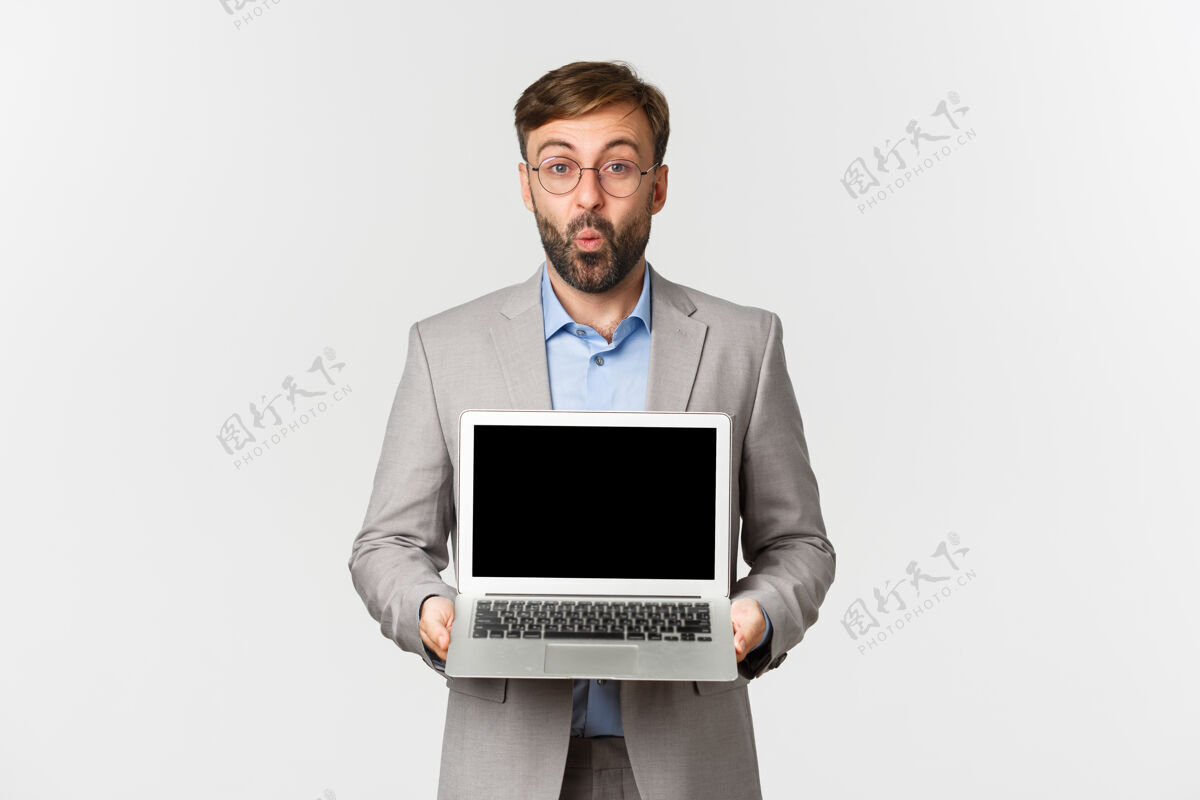 屏幕留着胡子 戴着眼镜 穿着西装的商人的肖像示范西装笔记本电脑
