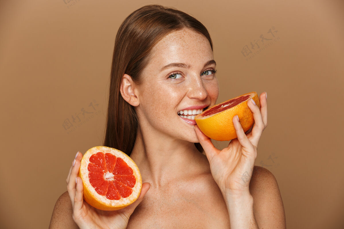 皮肤美丽的肖像 一个美丽健康的年轻裸体女子长着红色的头发显示切片柚子隔离在米色墙上多汁食物姿势
