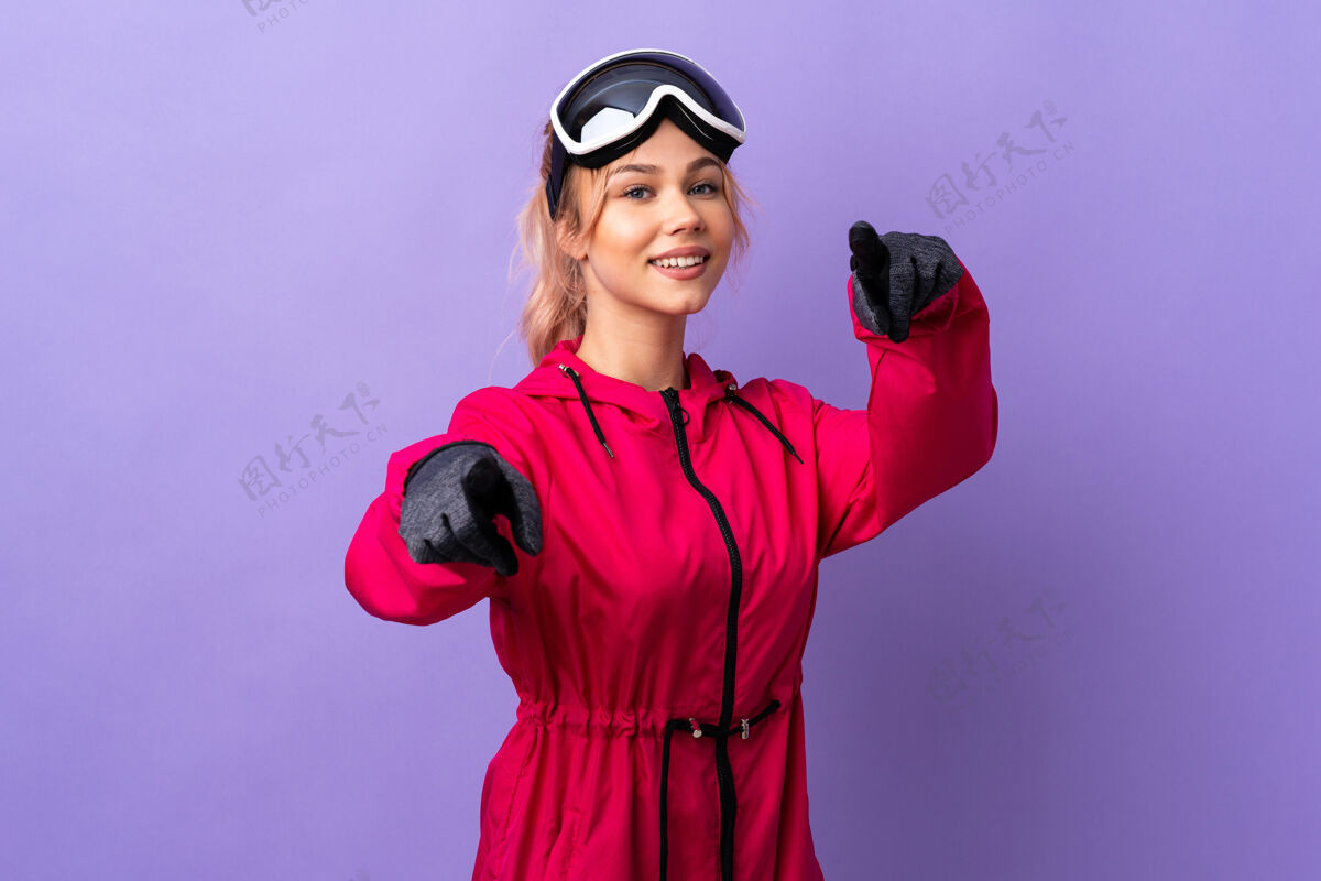 运动带着滑雪眼镜的滑雪者女孩在孤立的紫色指尖前面带着快乐的表情寒冷手指滑雪
