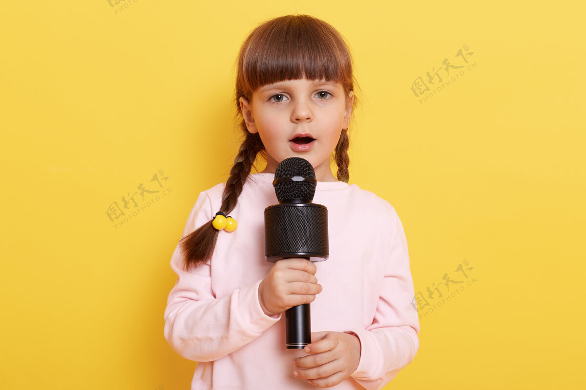 女小欧洲女孩儿在麦克风里唱歌 看起来很专注 想成为伟大的歌手 小可爱漂亮的艺术家安排演唱会 穿着淡粉色的毛衣声音享受歌手