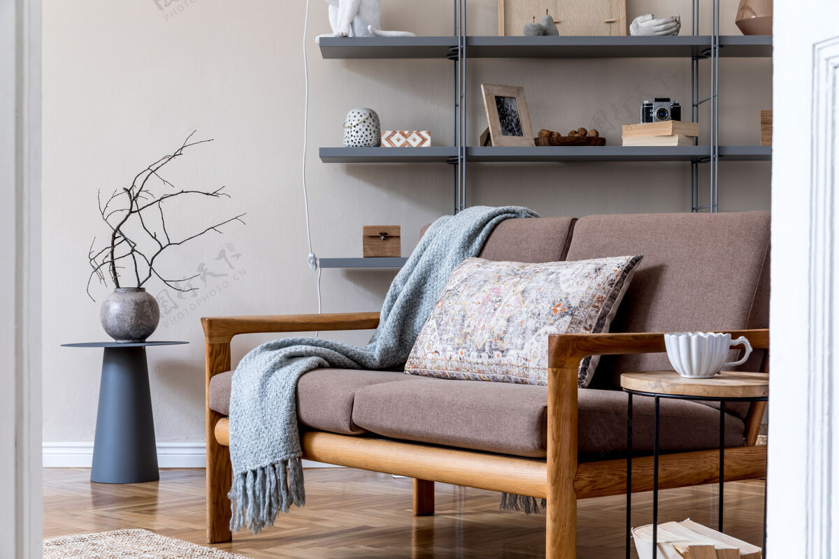 房子舒适公寓客厅的时尚内饰 棕色木沙发 咖啡桌 灰色书摊 枕头 格子布和优雅的配件米色和日式概念现代家居舞台沙发架子花瓶
