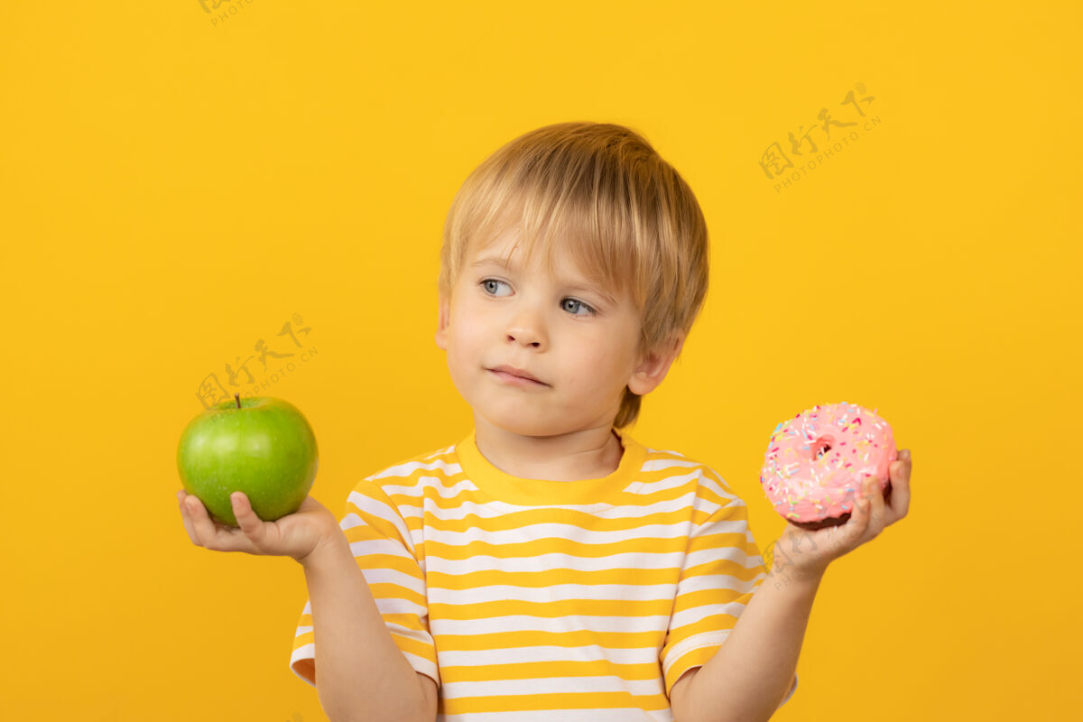 素食主义者快乐的孩子拿着甜甜圈和苹果食品苹果美味