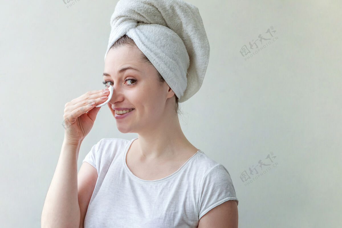 年轻头上戴着毛巾的微笑女人的美丽肖像 柔软健康的皮肤 用隔离在白色背景上的化妆棉卸妆肖像自然应用