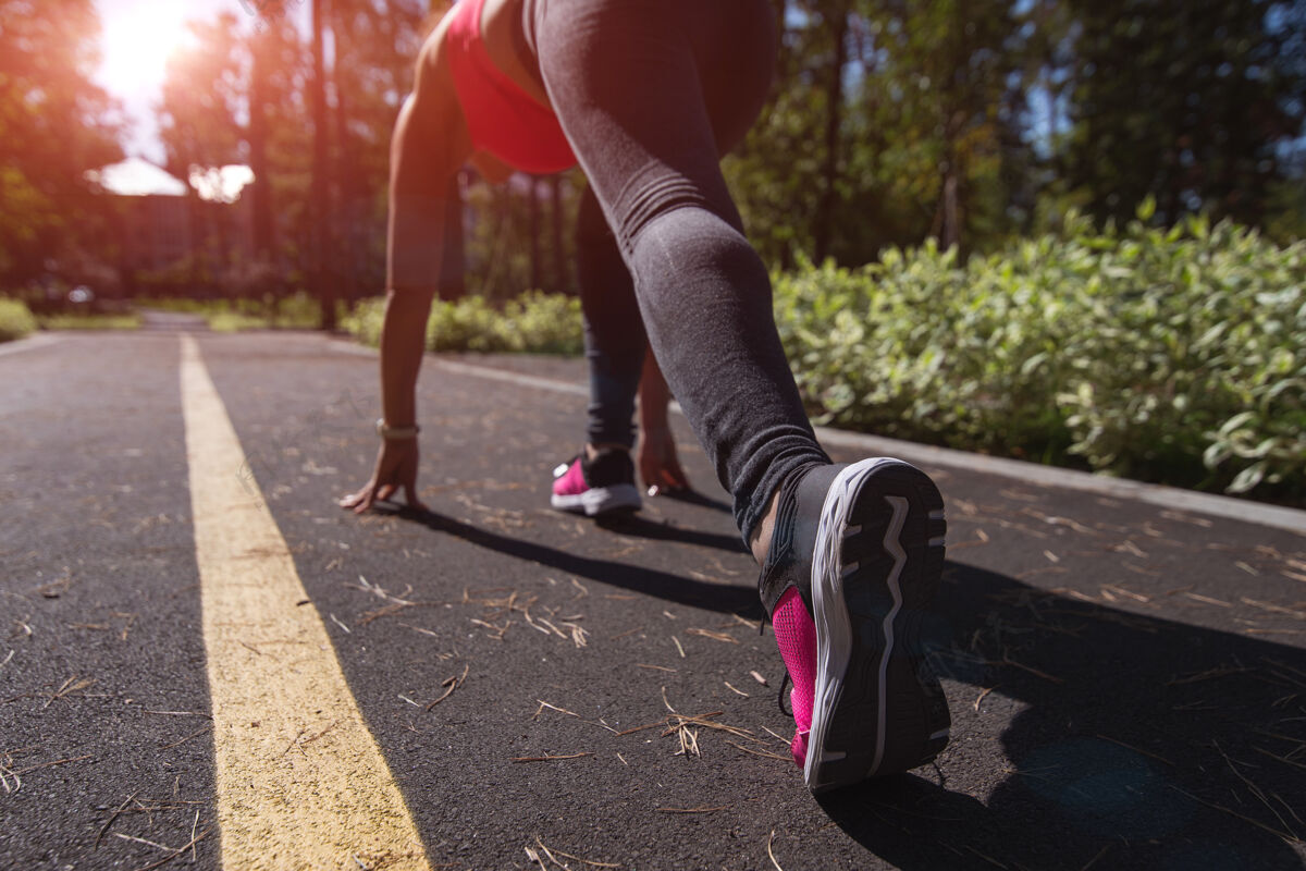 有氧运动运动型女跑步者在跑道上的起始位置户外日落或日出的背景健康马拉松城市