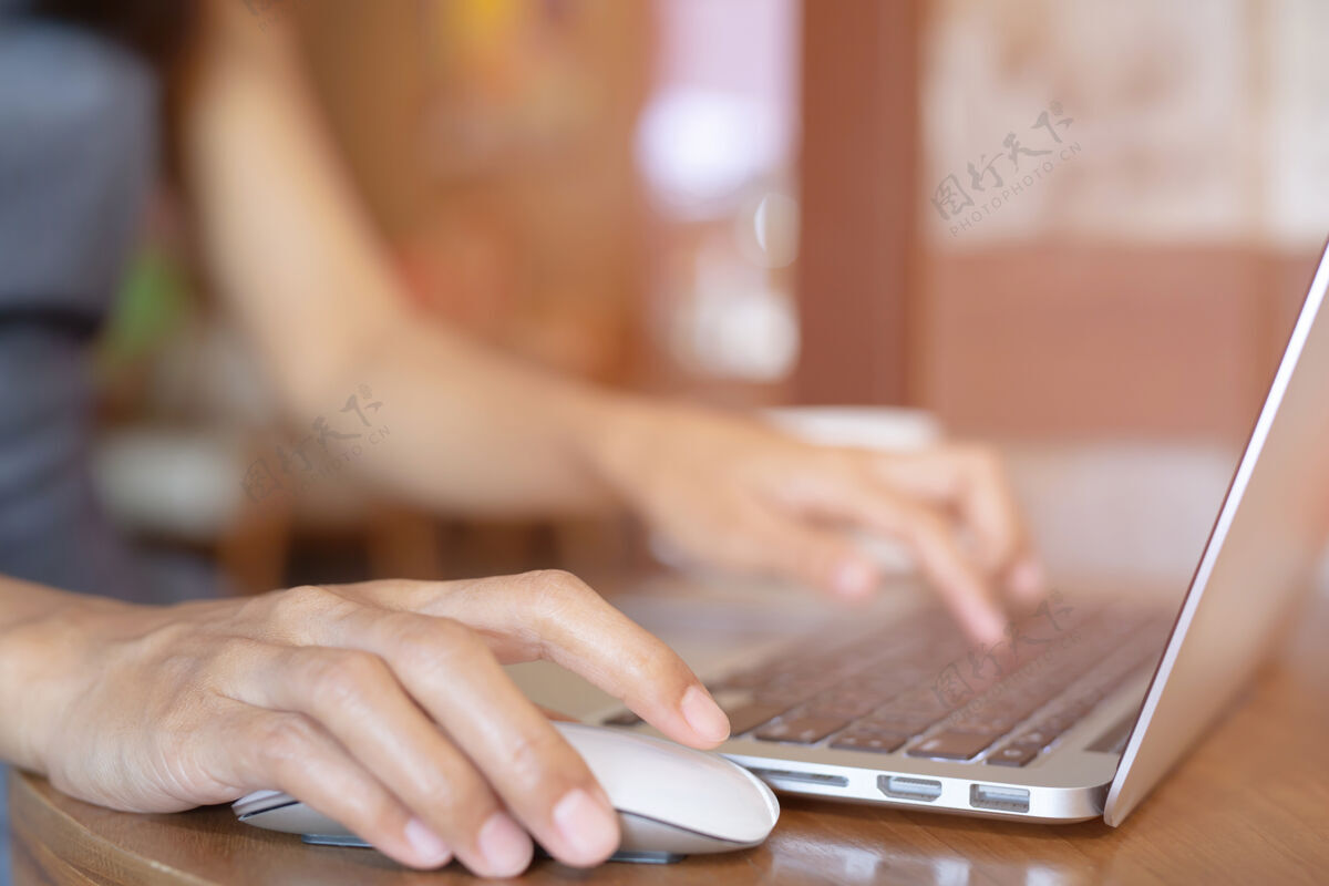 移动特写手上拿着人的女人在电脑笔记本上用手机坐在木地板上现代办公室商务