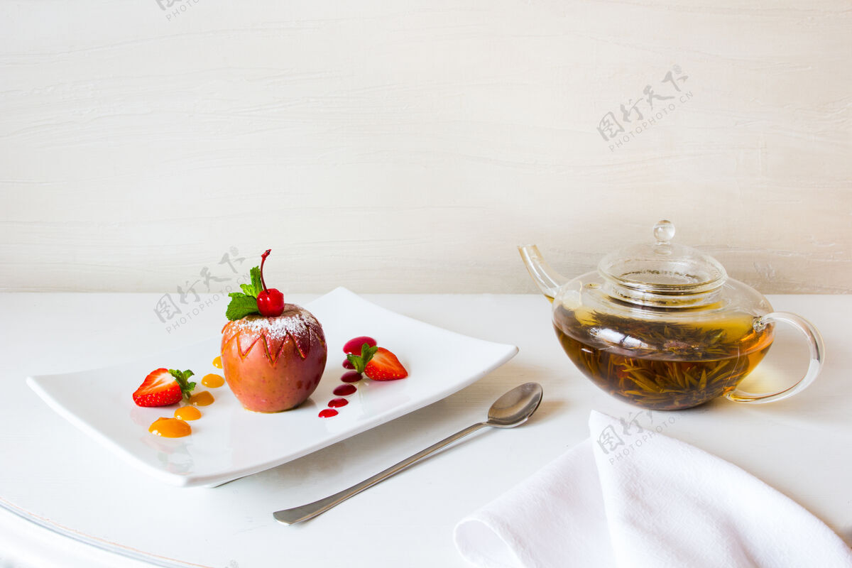 甜点烤苹果装饰草莓和花草茶白烹饪草药