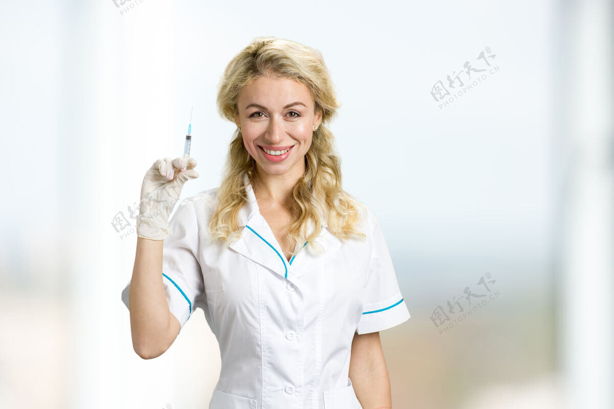 手术年轻护士拿着注射器的肖像美丽微笑的年轻医生拿着注射器 正视图女士保健朋友