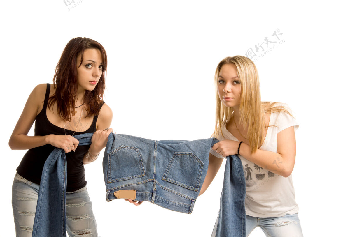 一起两个迷人的年轻女子正在为一条牛仔牛仔裤拉扯一条腿青年吊人