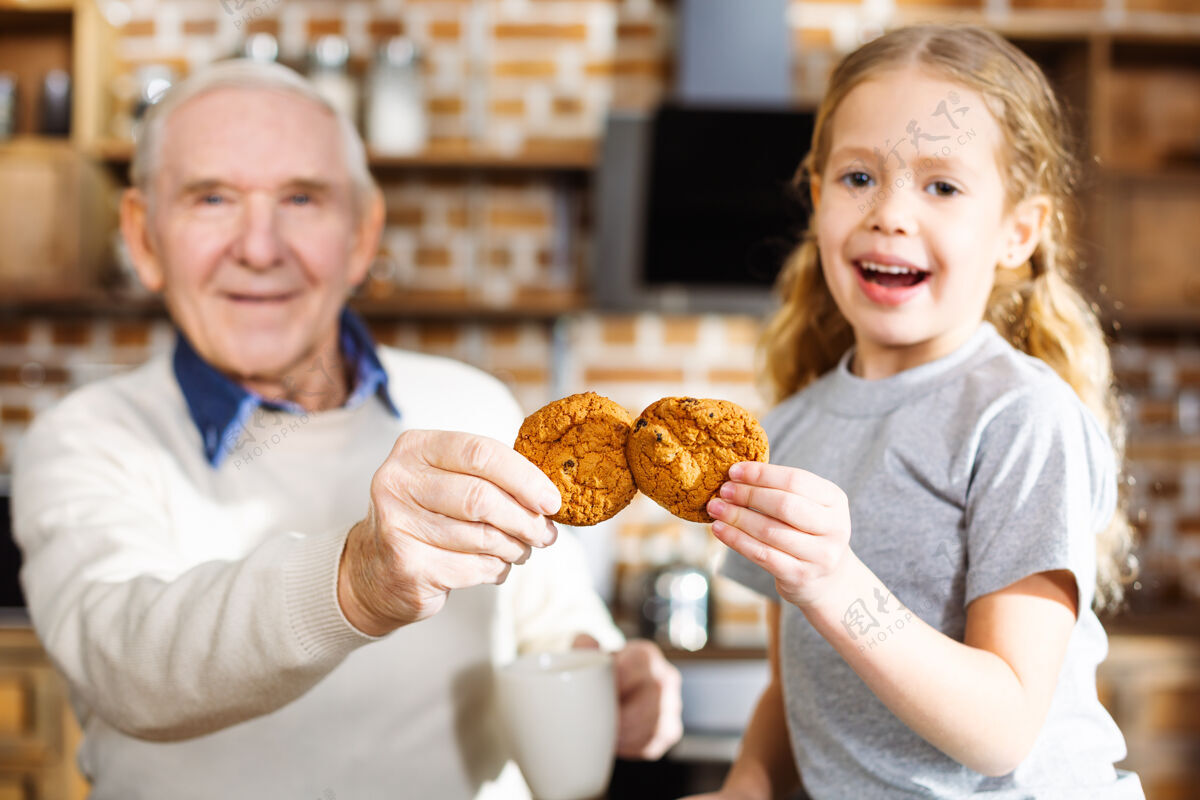 饼干快乐的小女孩和爷爷一起在家休息时吃饼干欢呼关系糕点
