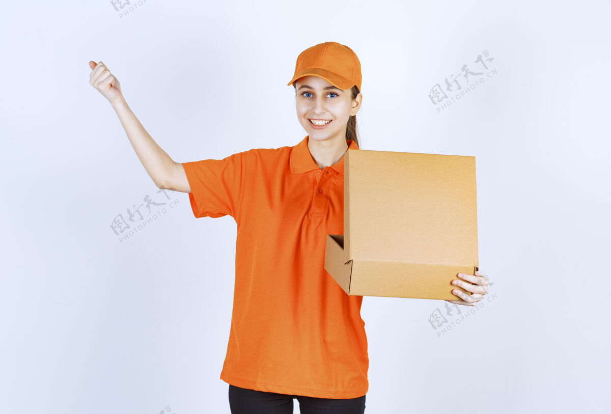 送货身着橙色制服的女信使 手里拿着一个打开的纸板箱 伸出拳头模特快乐员工