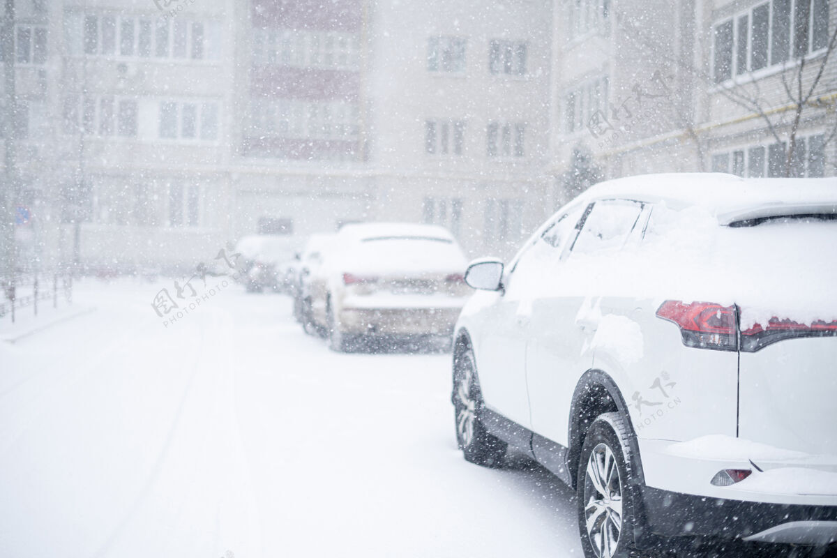 重冬天汽车被雪覆盖 外面有暴风雨交通城市住宅