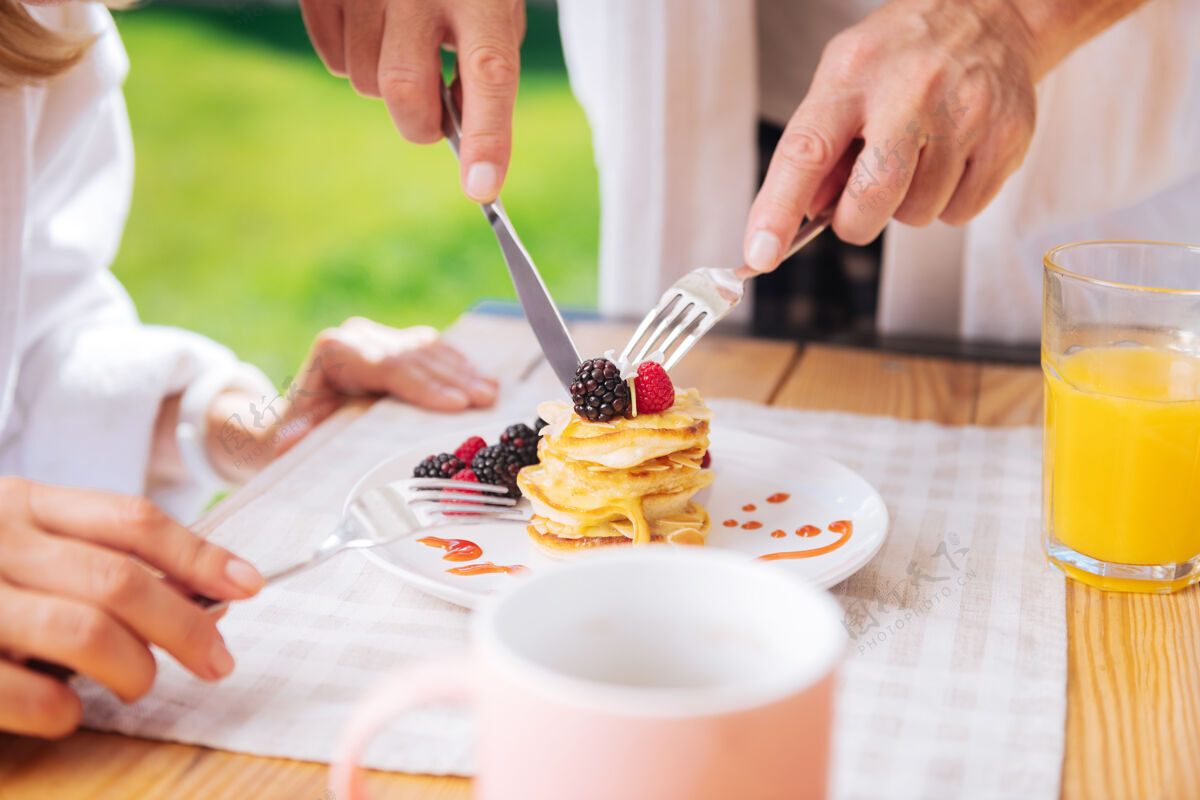 刀切薄煎饼爱心丈夫为妻子在露台上吃早餐 在上面切水果和蜂蜜薄煎饼早餐放松露台