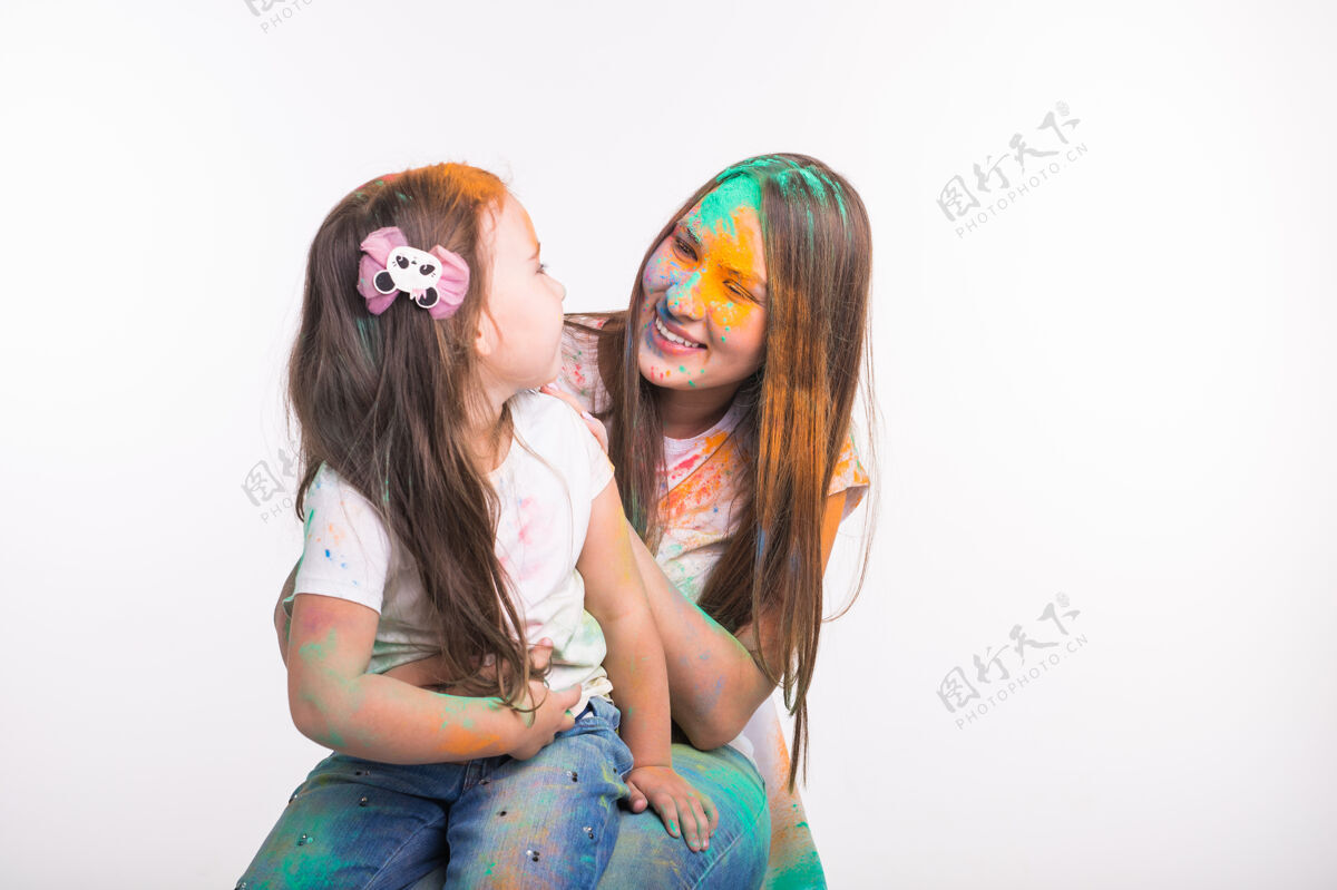 颜料家庭 爱和乐趣的概念-年轻女子与小女儿一起微笑 在胡里节的颜色肮脏无忧无虑神圣粉末