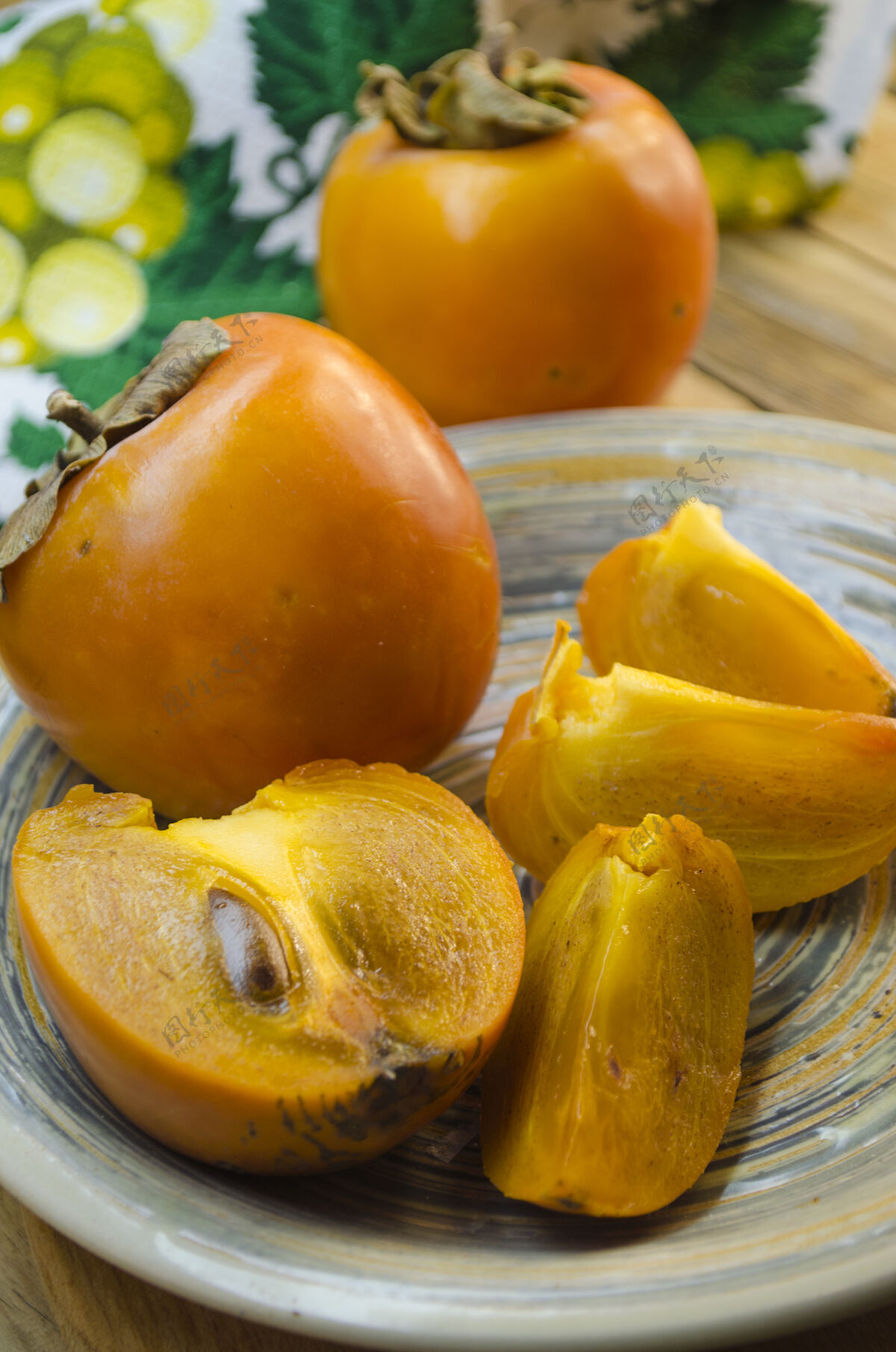 食物成熟的柿子放在木桌上的盘子里产品异国情调盘子