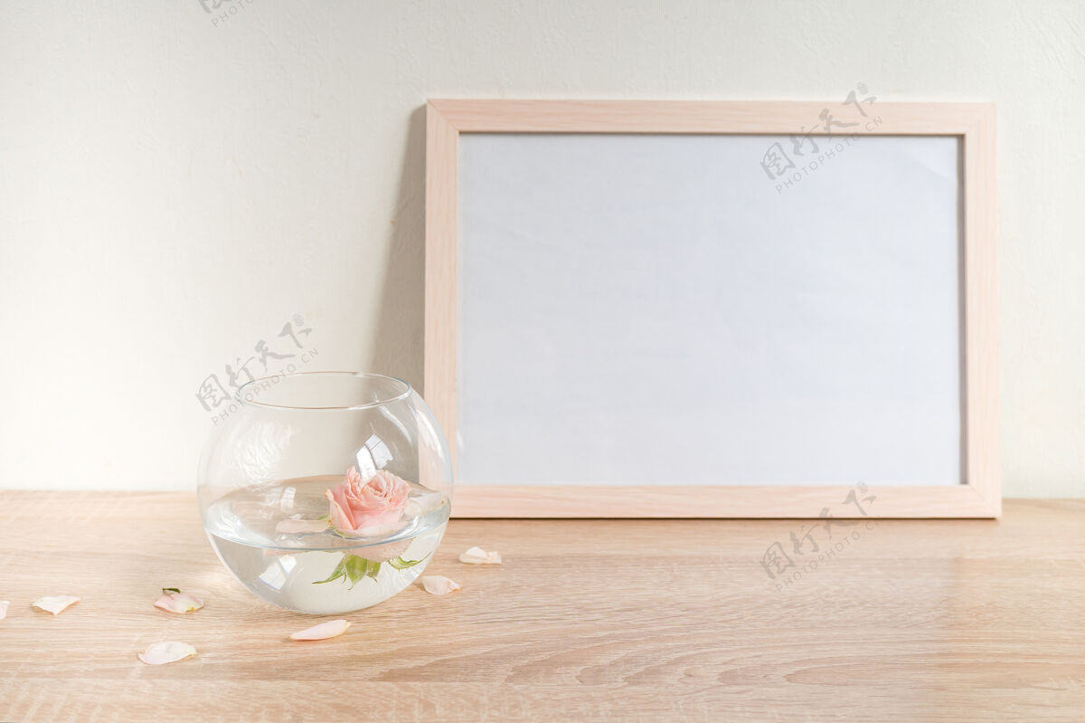 房子木桌上的肖像白色相框模型现代玻璃花瓶 带有玫瑰白墙背景 斯堪的纳维亚内部展览画框地板