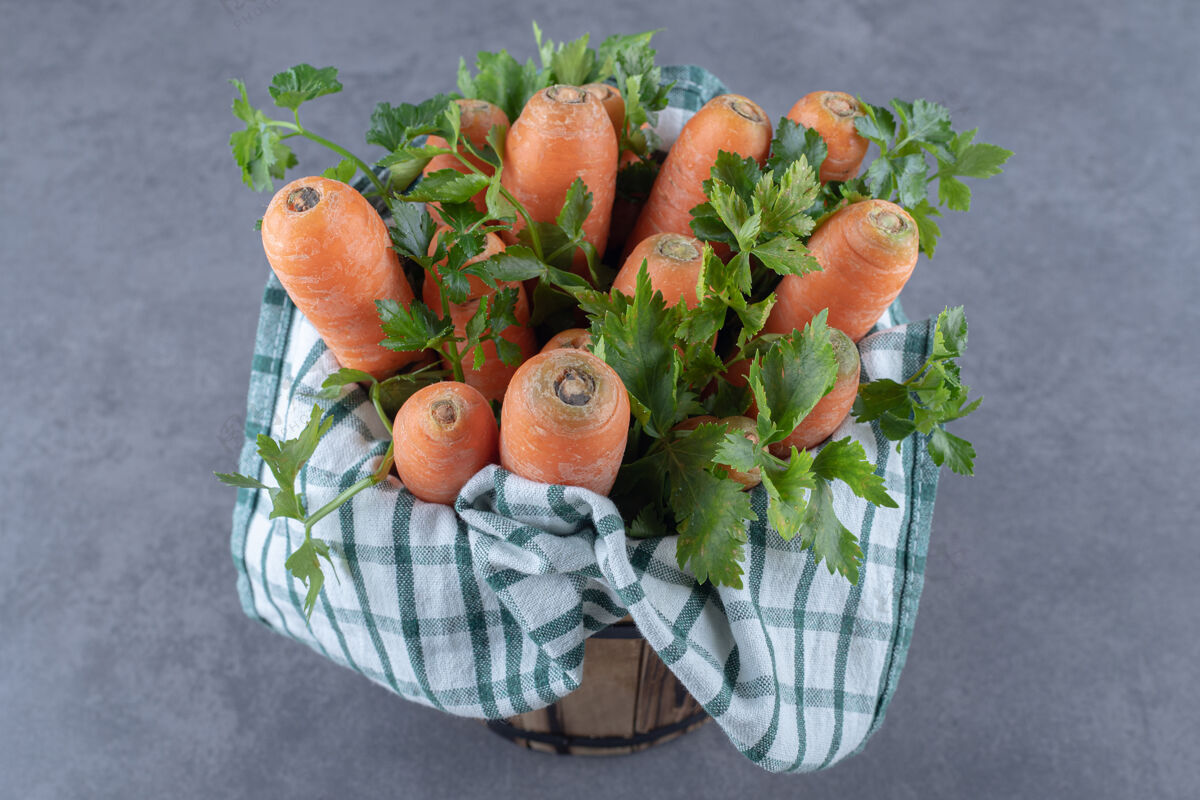 胡萝卜胡萝卜和叶子放在毛巾上的桶里 放在大理石的表面上美味生的美味