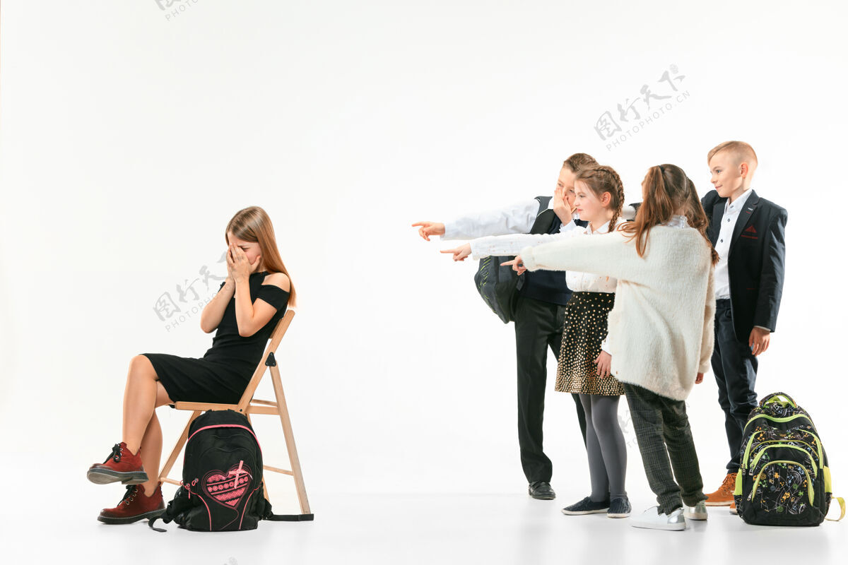 残忍小女孩独自坐在椅子上 忍受着欺凌 而孩子们却在嘲笑她悲伤的小女孩坐在白色背景下的演播室里问题社会女孩