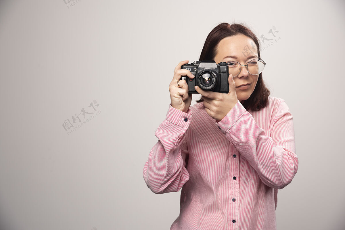 年轻用白色相机拍照的女人高质量的照片时尚女人摄影师