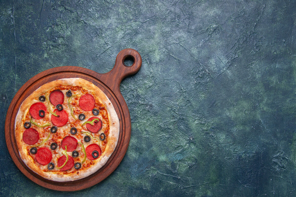 晚餐美味的比萨饼放在右边的木砧板上 深蓝色的表面 有自由空间奶酪肉比萨饼