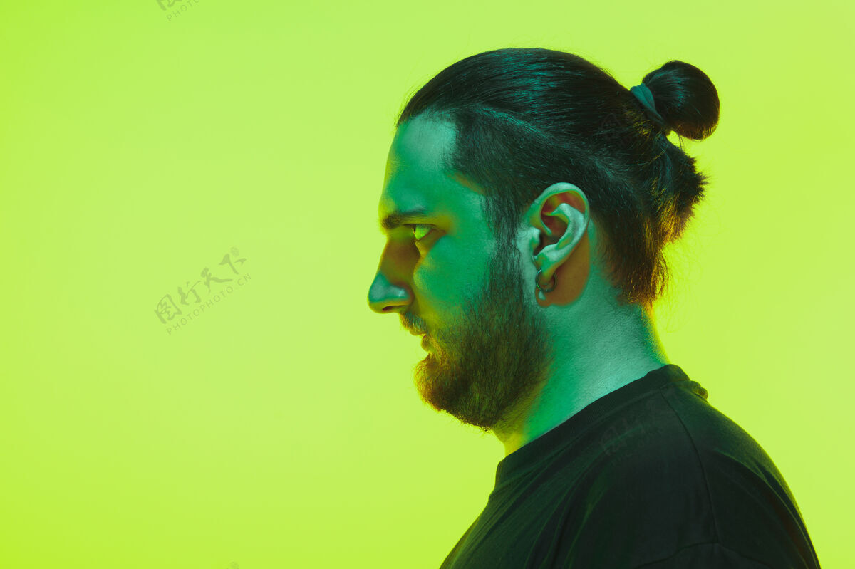 男性一个男人的肖像 在绿色的工作室背景上用五颜六色的霓虹灯冷静严肃的男模特黑肖像眼睛